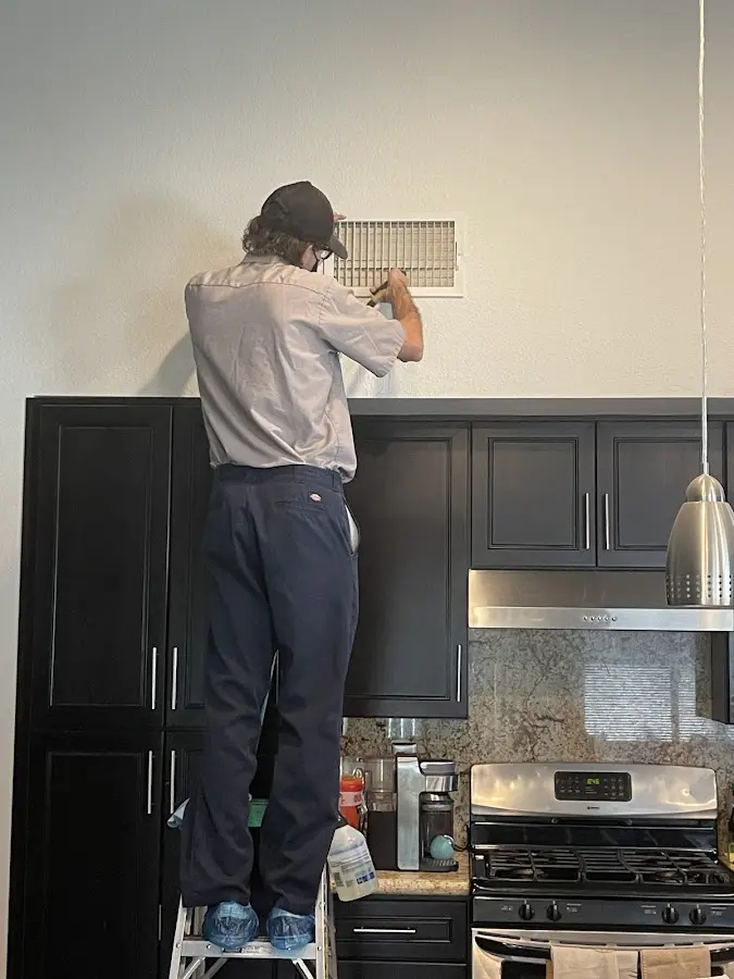 Technician inspecting an air vent during HVAC service in Bellview